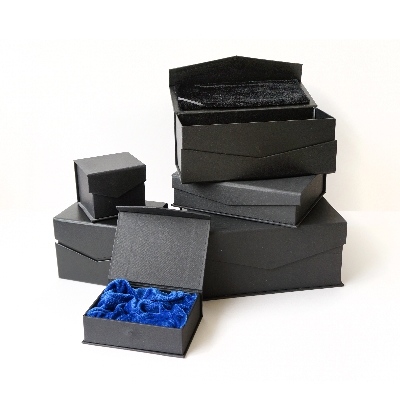 Dovanų dėžutės, kuriose įpakuojami gaminiai. Dėžučių išorė juoda, o  vidus tamsiai mėlynos spalvos