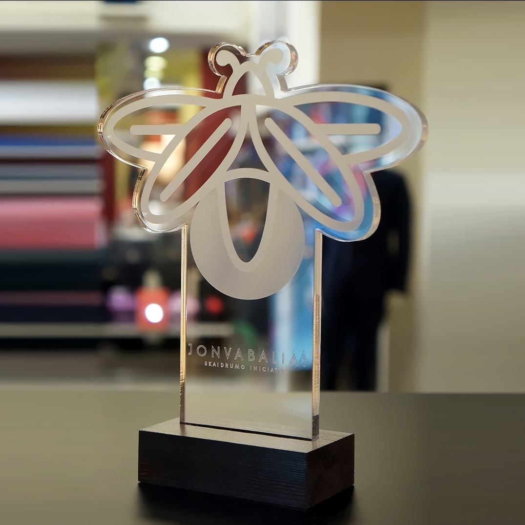 Individuliai graviruotas stiklo apdovanojimas su 'Jonvabaliai' iniciatyvos simbolika, pateiktas ant stilingo medinio stovo, kuris yra puikus pasirinkimas korporatyviniams apdovanojimams.